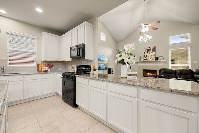 kitchen with open floor plan, white cabinets, light stone countertops, a lit fireplace, and black appliances