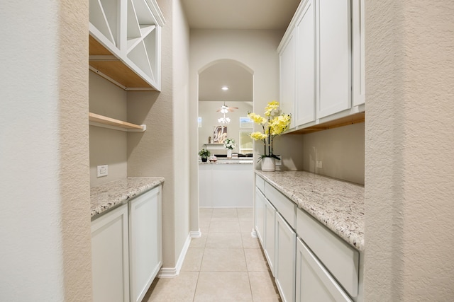 bar featuring arched walkways, light tile patterned flooring, and baseboards