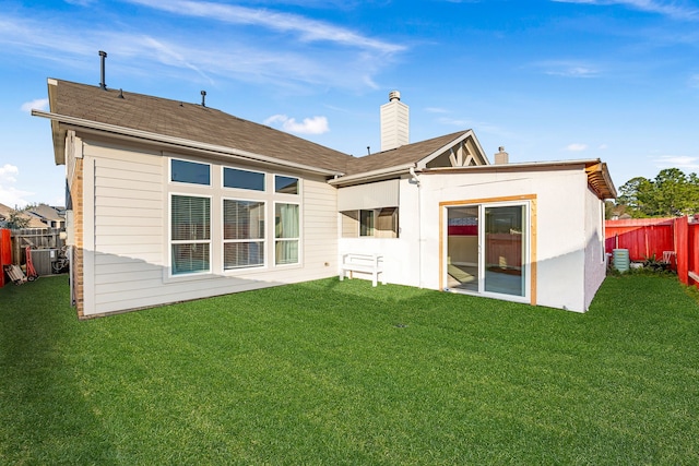 back of house featuring a yard, central AC, fence, and a chimney