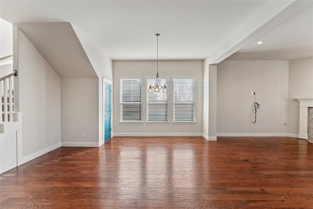 unfurnished dining area with a fireplace, dark hardwood / wood-style floors, and a notable chandelier