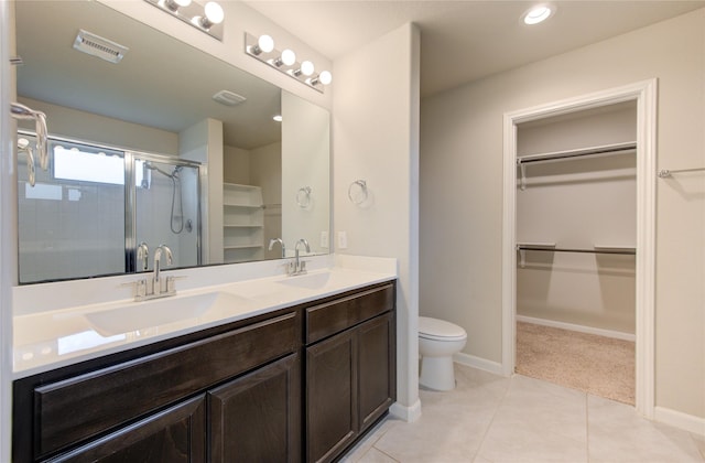 bathroom featuring vanity, a shower with door, toilet, and tile patterned floors