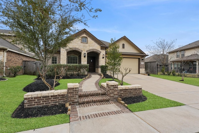 french country home with concrete driveway, an attached garage, a front yard, fence, and stone siding