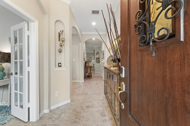 hallway with visible vents, arched walkways, baseboards, and ornamental molding