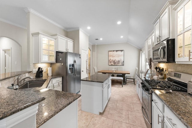 kitchen featuring stainless steel appliances, glass insert cabinets, white cabinetry, a sink, and a kitchen island