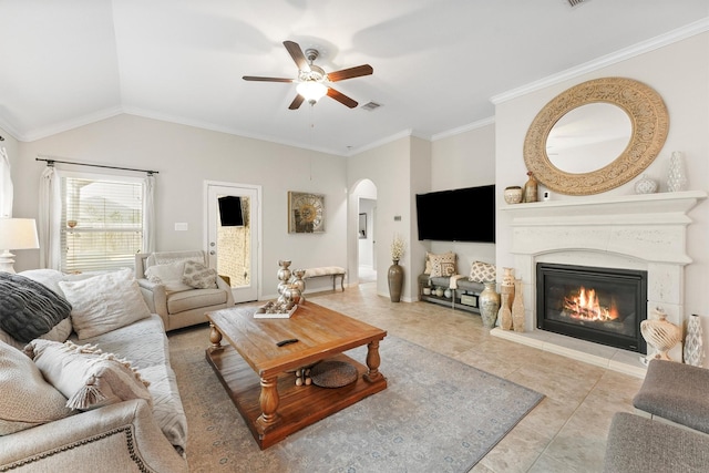 living area with arched walkways, visible vents, a ceiling fan, ornamental molding, and a glass covered fireplace