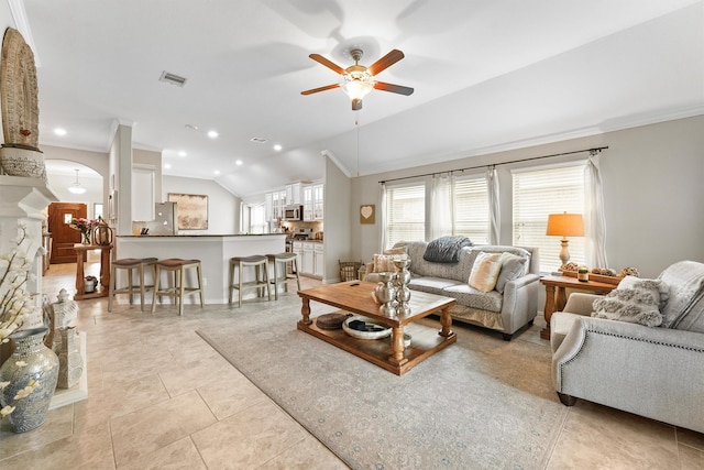 living area featuring arched walkways, crown molding, lofted ceiling, visible vents, and a ceiling fan