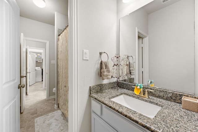 bathroom with toilet, washer / clothes dryer, and vanity