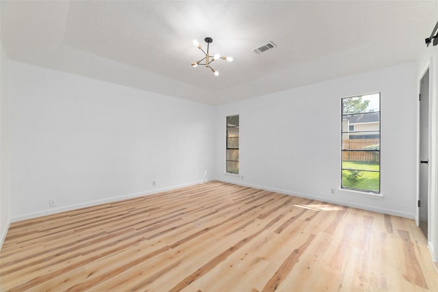 empty room featuring a chandelier and light hardwood / wood-style flooring