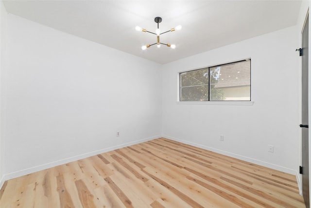 empty room with light hardwood / wood-style floors and a chandelier