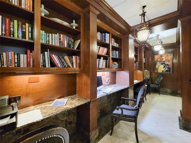 office space featuring wood walls, crown molding, and built in desk