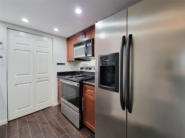 kitchen featuring brown cabinets, dark countertops, recessed lighting, appliances with stainless steel finishes, and wood tiled floor