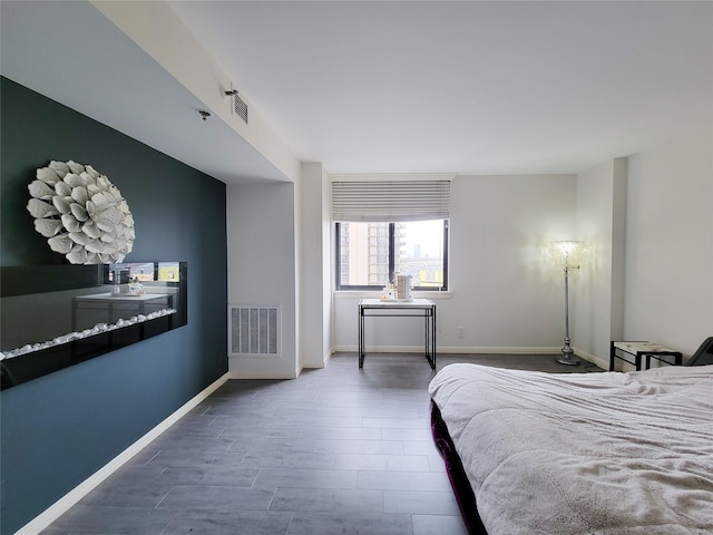 bedroom with wood finished floors, visible vents, and baseboards