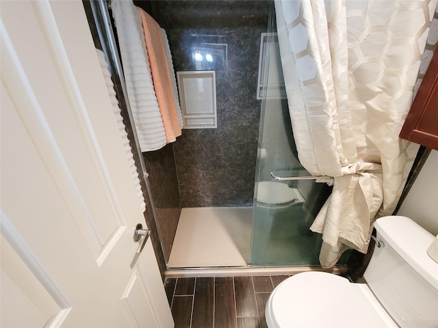 full bathroom featuring a shower stall, toilet, and wood tiled floor