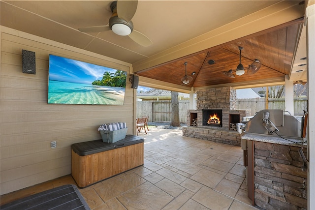 view of patio with ceiling fan, an outdoor kitchen, an outdoor stone fireplace, and area for grilling