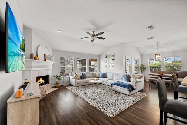 living room featuring a tile fireplace, a healthy amount of sunlight, vaulted ceiling, and dark hardwood / wood-style floors