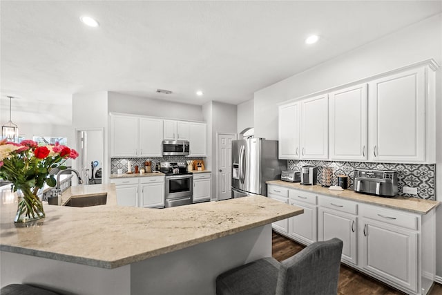 kitchen with appliances with stainless steel finishes, white cabinets, and a kitchen bar