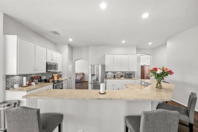 kitchen with appliances with stainless steel finishes, white cabinetry, a breakfast bar area, and tasteful backsplash