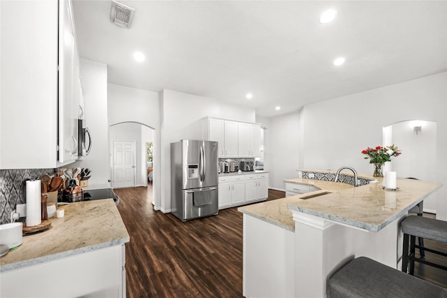 kitchen with stainless steel appliances, light stone countertops, sink, white cabinets, and a kitchen breakfast bar