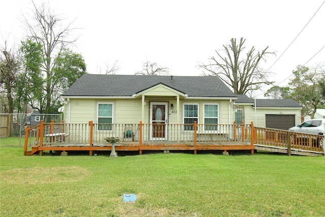 view of front of home with an attached garage, roof with shingles, a front lawn, and fence