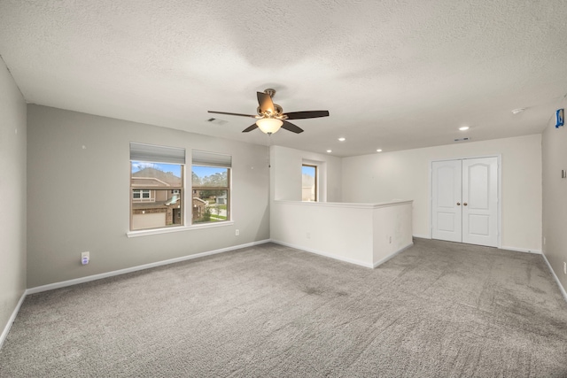 carpeted empty room featuring a textured ceiling and ceiling fan