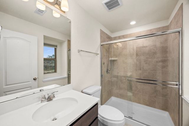 bathroom featuring vanity, a shower with shower door, and toilet