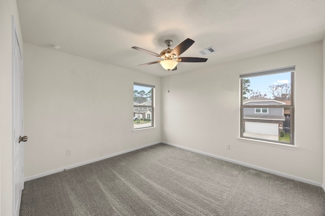 spare room with a textured ceiling, carpet flooring, and ceiling fan