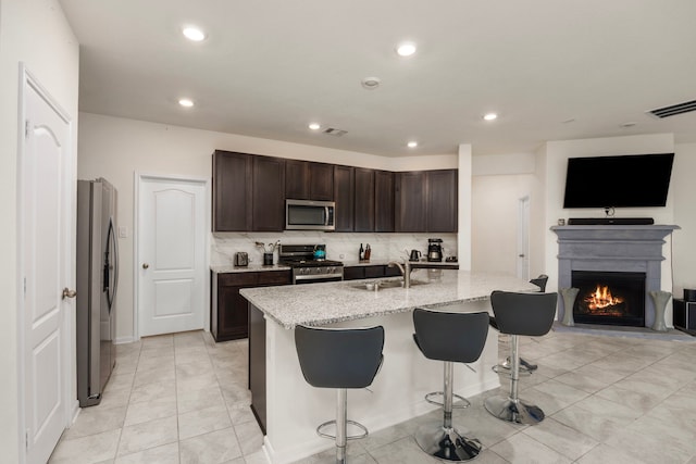 kitchen with sink, appliances with stainless steel finishes, a breakfast bar area, and an island with sink