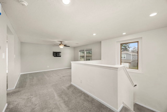 carpeted spare room with a textured ceiling and ceiling fan