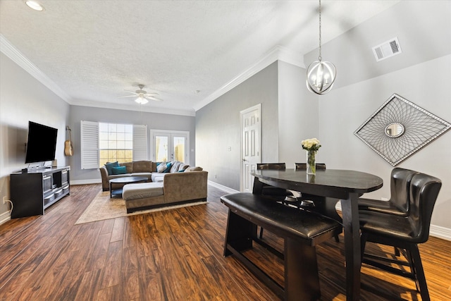 living room with ceiling fan with notable chandelier, crown molding, dark wood-type flooring, and a textured ceiling