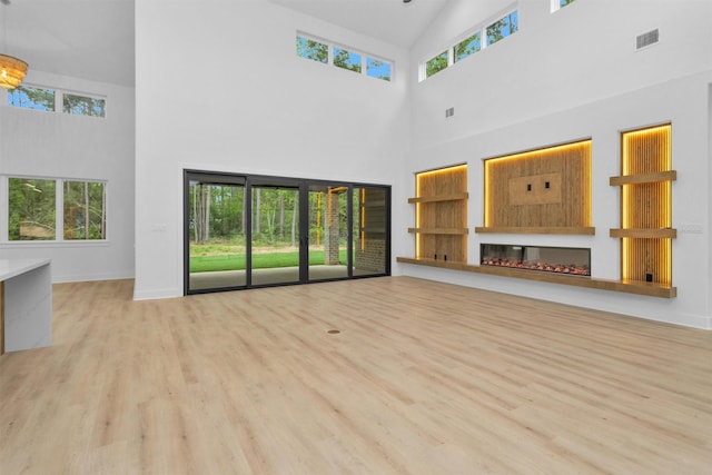 19918 Live Oak Bnd, Magnolia, TX 77355 - unfurnished living room featuring a wealth of natural light, wood finished floors, and a glass covered fireplace