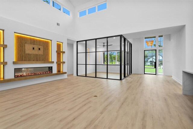 19918 Live Oak Bnd, Magnolia, TX 77355 - unfurnished living room with a ceiling fan, a glass covered fireplace, baseboards, and wood finished floors