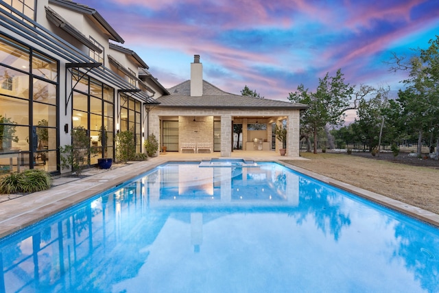 pool at dusk featuring a patio area