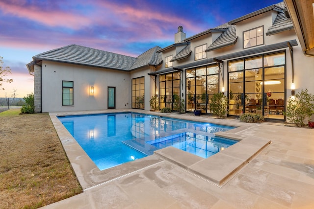 pool at dusk with a patio area and a jacuzzi