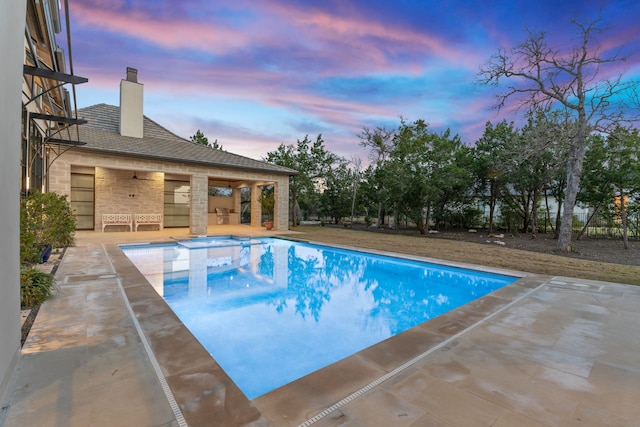 pool at dusk featuring a patio area