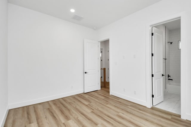 unfurnished bedroom with connected bathroom and light hardwood / wood-style floors