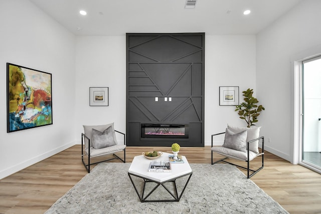 sitting room featuring hardwood / wood-style flooring and a large fireplace