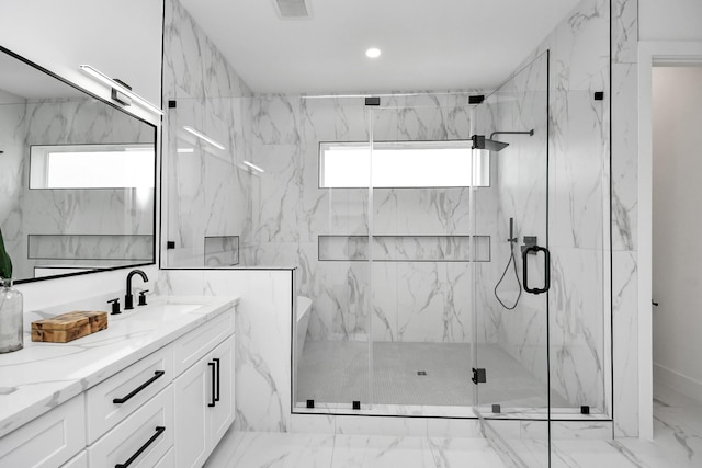 bathroom with vanity, a shower with shower door, and a healthy amount of sunlight