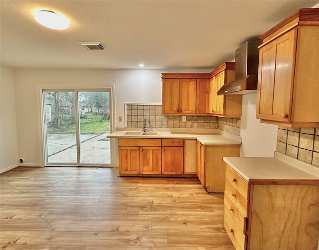 kitchen featuring sink, wall chimney exhaust hood, light hardwood / wood-style floors, and backsplash