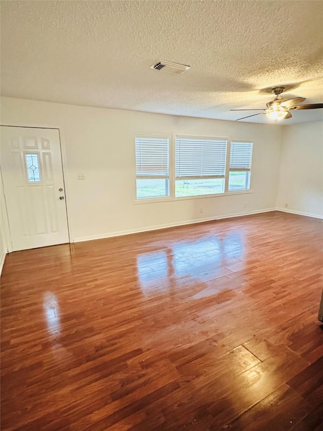 interior space with a textured ceiling, plenty of natural light, ceiling fan, and dark hardwood / wood-style floors