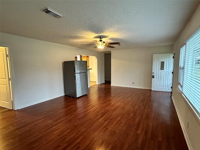 unfurnished living room featuring ceiling fan, dark wood-type flooring, and a textured ceiling