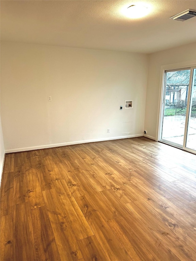 spare room featuring a textured ceiling and light hardwood / wood-style floors