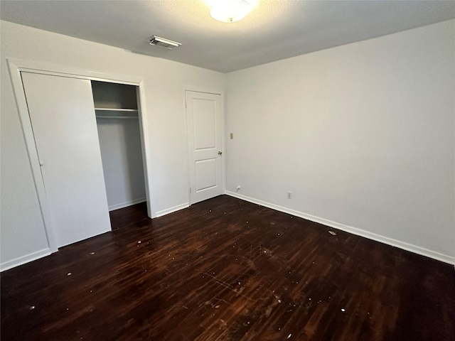 unfurnished bedroom with dark wood-type flooring and a closet