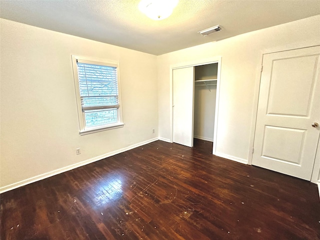 unfurnished bedroom featuring a textured ceiling, a closet, and dark hardwood / wood-style floors