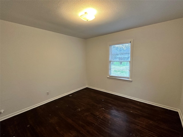 spare room with dark wood-type flooring and a textured ceiling