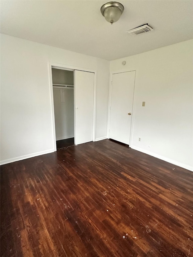 unfurnished bedroom featuring a closet and dark wood-type flooring