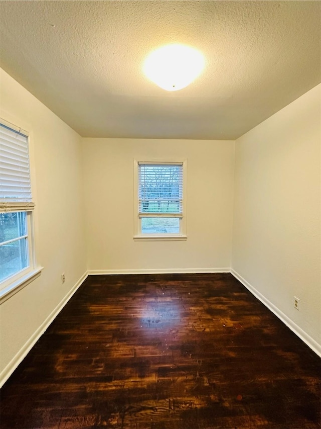 unfurnished room with dark hardwood / wood-style flooring and a textured ceiling