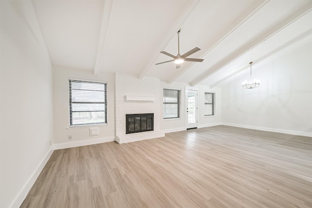 unfurnished living room featuring a fireplace, lofted ceiling with beams, light wood-style floors, baseboards, and ceiling fan with notable chandelier