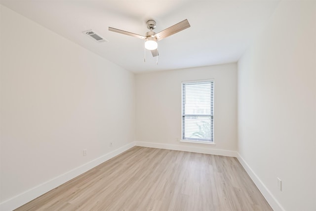 spare room featuring light wood-style flooring, a ceiling fan, visible vents, and baseboards