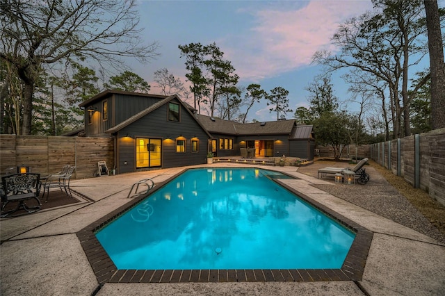 pool at dusk featuring a patio area, a fenced backyard, and a fenced in pool