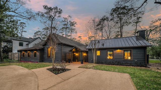 view of front of home featuring a standing seam roof, metal roof, a chimney, and a front yard